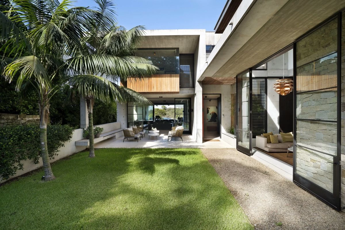 Spacious courtyard with green grass and palm trees, connected to indoor seating areas - 16 Iluka Road, Mosman, NSW 2088