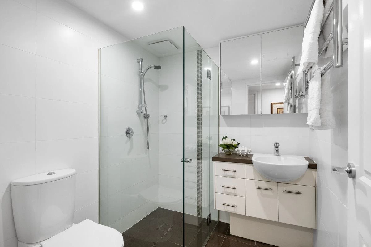 A clean and modern bathroom with a glass-enclosed shower, toilet, and storage spaces - 18/1A Bond Street, Mosman, NSW 2088